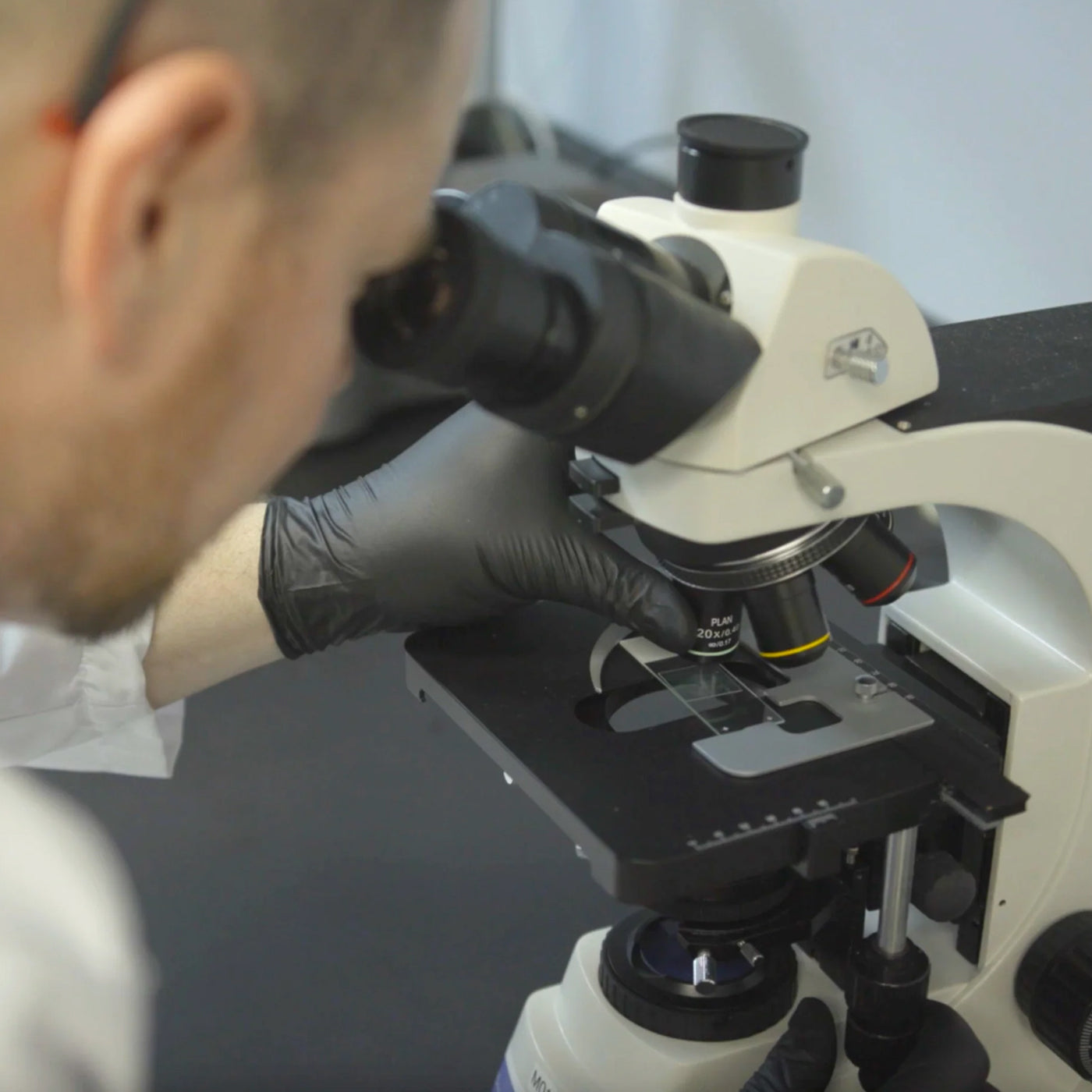 Man in lab looking through telescope