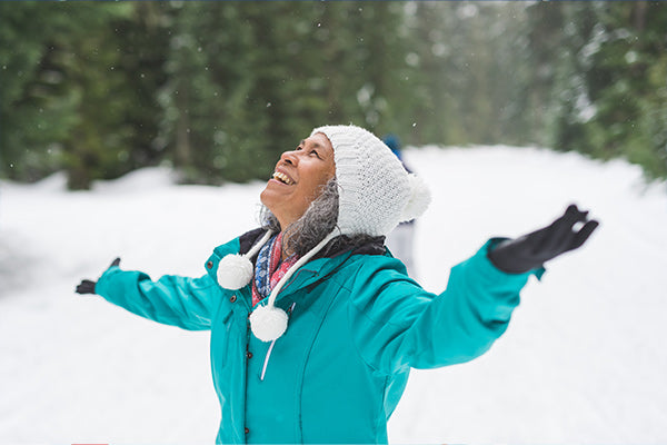 Middle-aged woman standing outside in the snow smiling.