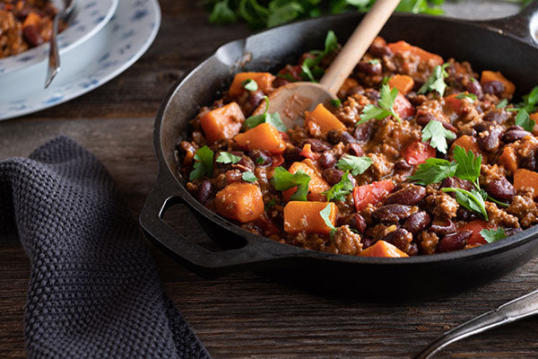 Bowl of chili with sweet potatoes on top on a table 