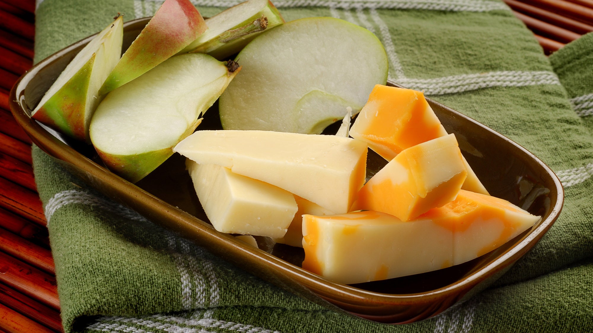 Apples and cheese on a green picnic blanket